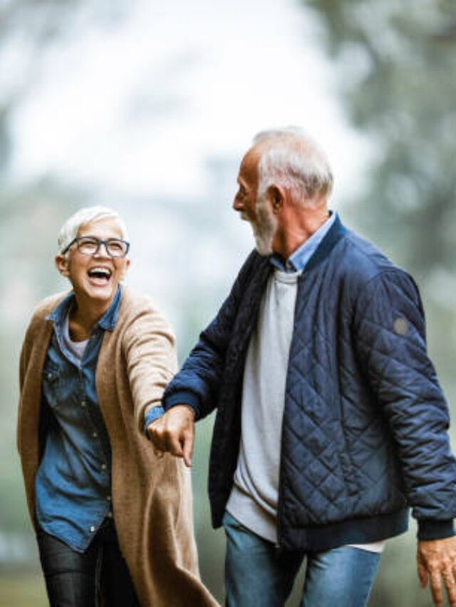 Cheerful senior couple having fun in the park. Focus is on woman. Copy space.