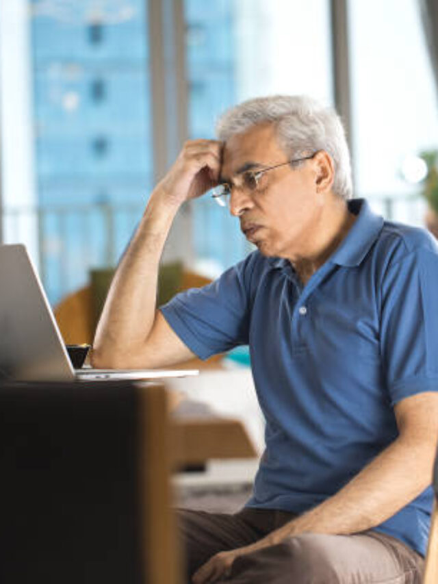 Displeased senior man using laptop at home